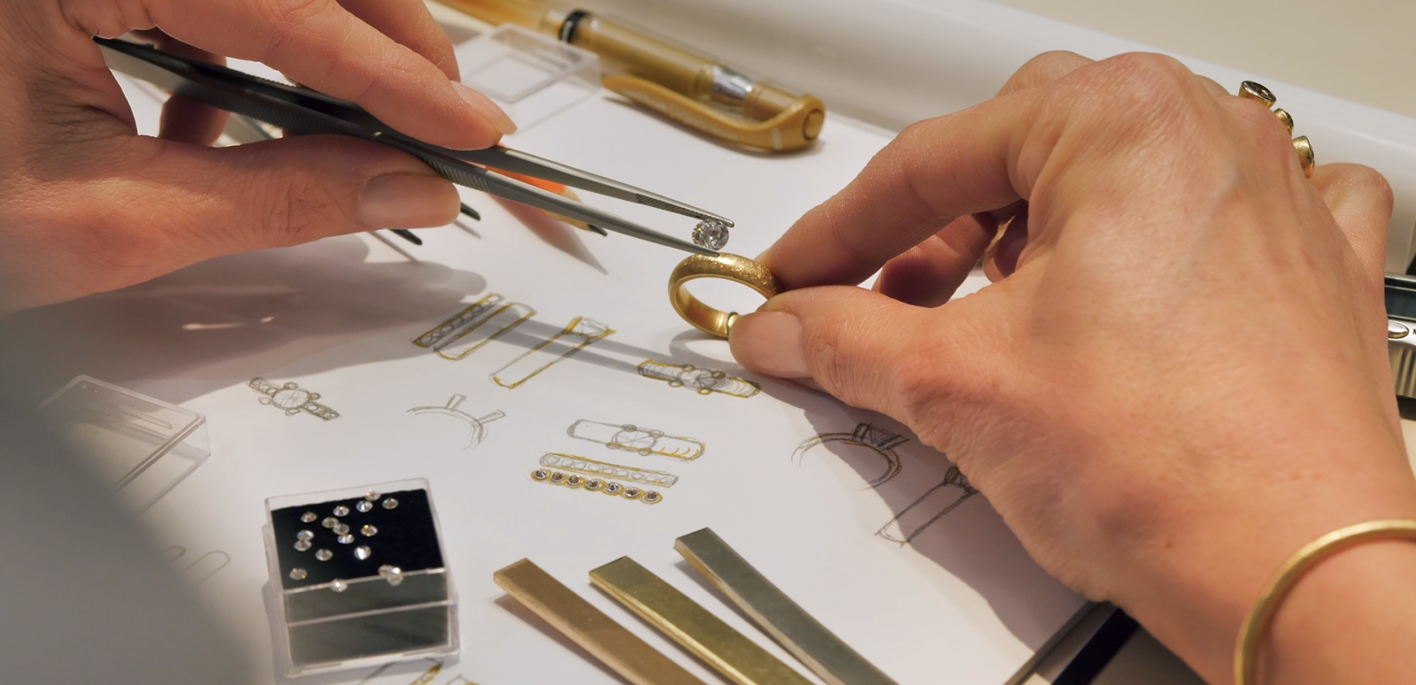 Diamant tenu avec une pince au-dessus d’une bague, accompagné de croquis du modèle de bague envisagé